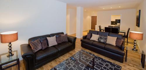 a living room with two black leather couches at Trinity Quay Apartments in Aberdeen