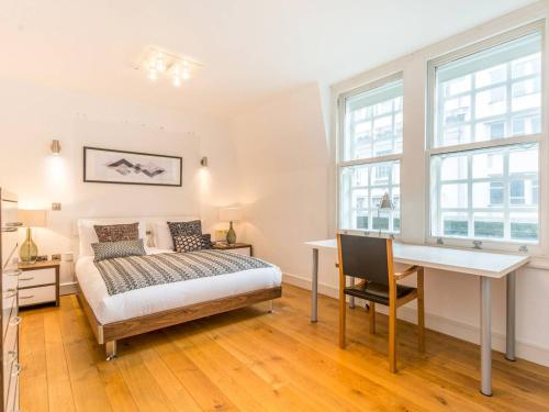 a bedroom with a bed and a desk and windows at Pass The Keys Gorgeous 3-bed with large roof terrace, very central in London