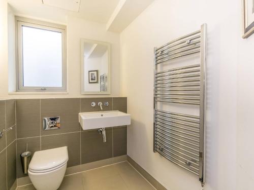 La salle de bains est pourvue de toilettes, d'un lavabo et d'une fenêtre. dans l'établissement Pass The Keys Gorgeous 3-bed with large roof terrace, very central, à Londres