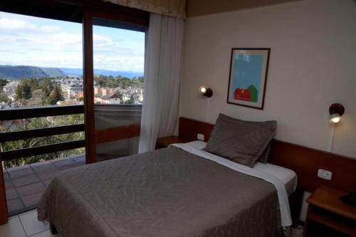 um quarto com uma cama e uma grande janela em Apartamento Pousada do Serrano em Gramado