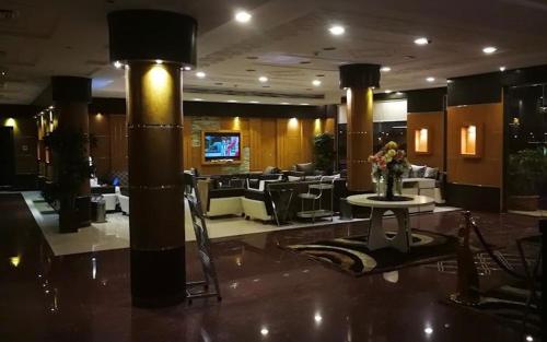 تاج الحمراء للاجنحة الفندقية Taj Al Hamra Hotel Suites في الرياض: لوبي فندق مع طاولة وكراسي
