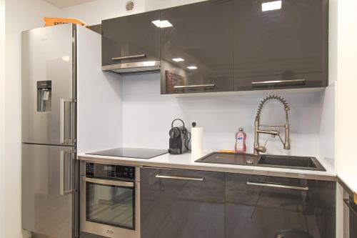 une cuisine avec un réfrigérateur en acier inoxydable et un évier dans l'établissement ZenBNB / La Gallery /Proche Suisse, à Saint-Julien-en-Genevois