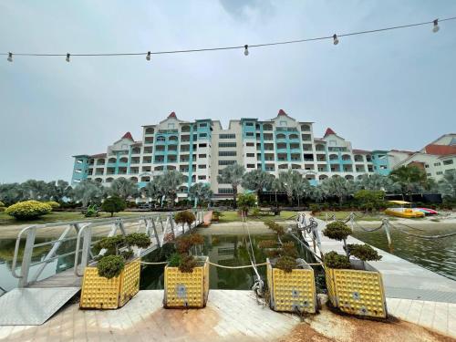 a large building with yellow chairs in front of a body of water at Laguna Raudhah Apartment in Lumut