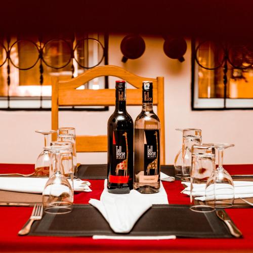 two bottles of wine sitting on a table with glasses at Randa Family House - Moshi in Himo