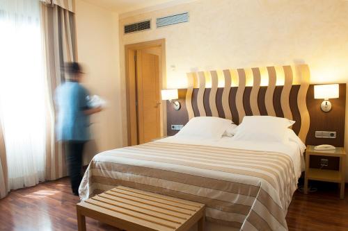 a man standing in a hotel room with a large bed at Hotel Duran in Figueres