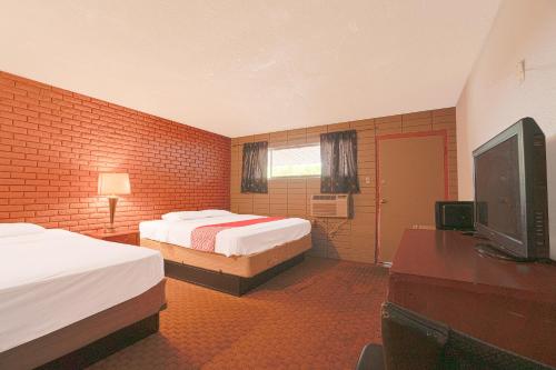 a hotel room with two beds and a flat screen tv at Town & Country Motel Bossier City by OYO in Bossier City