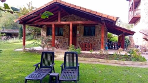 three chairs sitting in the grass in front of a building at Apartamentos la casa de los ríos in Liérganes