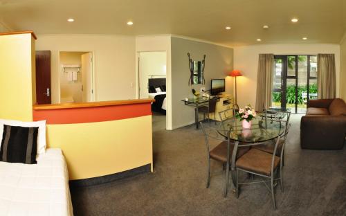 a hotel room with a bed and a dining room at Chancellor Motor Lodge and Conference Centre in Palmerston North