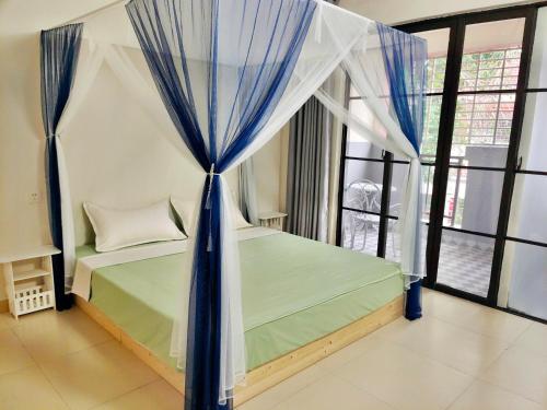 a bedroom with a canopy bed with blue curtains at 闲肆民宿 in Sanya