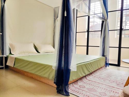 a bed with a canopy in a room with windows at 闲肆民宿 in Sanya