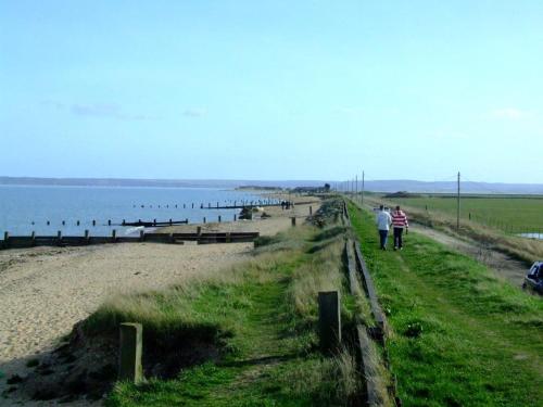 two people walking on a beach next to the water at Seaview in Leysdown-on-Sea