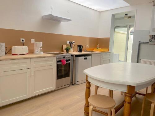 une cuisine avec une table blanche et un comptoir blanc dans l'établissement Maison cosy 5 chambres exterieur centre ville, à Croix