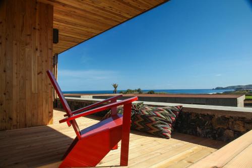 a red chair sitting on the deck of a house at Santa Barbara Eco-Beach Resort in Ribeira Grande