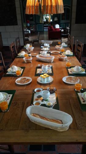 een lange houten tafel met borden eten erop bij Chambres d'Hôtes Manoir de Beaumarchais in Les Chapelles-Bourbon