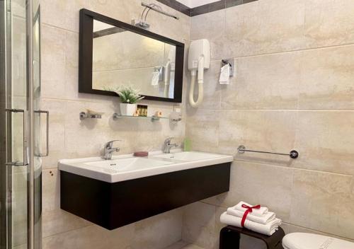 a bathroom with a sink and a mirror and a toilet at Hotel Degli Haethey in Otranto