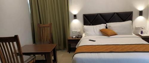 a hotel room with a large bed and a table at Hotel Le Grandeur in Bengaluru
