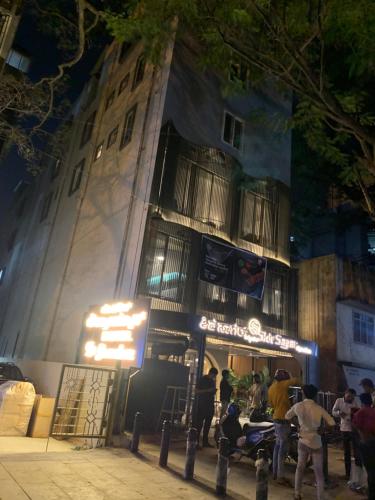 a group of people standing outside of a building at night at Hotel Le Grandeur in Bengaluru