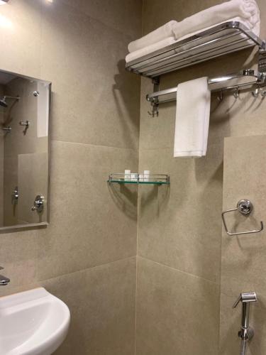 a bathroom with a sink and a toilet and a mirror at Hotel Le Grandeur in Bangalore