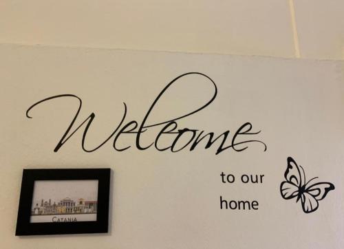 a welcome to our home sign on a wall with a butterfly at THE AIRPORT HOUSE in Catania