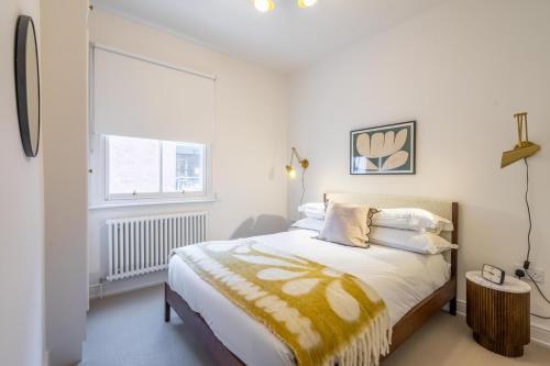 a bedroom with a bed with a yellow blanket and a window at 17 Trinity Lane in York