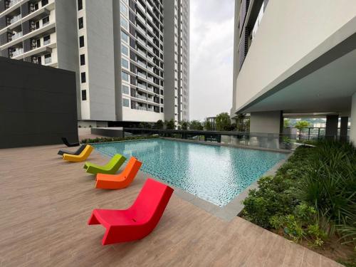 basen z kolorowymi krzesłami obok budynku w obiekcie Mid Valley Luxury 6pax Resort谷中城奢华风格套房 w Kuala Lumpur