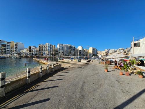 a street next to a beach with buildings at Stunning Seafront Portomaso Apartment in Paceville