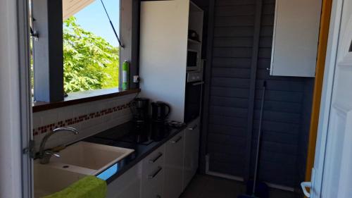 una pequeña cocina con fregadero y ventana en Bungalow de 2 chambres avec vue sur la mer jardin clos et wifi a Anse Bertrand, en Anse-Bertrand