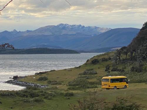 una furgoneta amarilla estacionada en una colina junto a un cuerpo de agua en Camperbus Apawata, en Puerto Natales