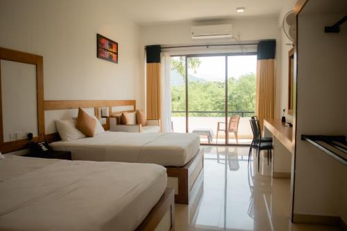 a hotel room with two beds and a large window at G.M.T.SORABORA VILLAGE HOTEL in Mahiyangana