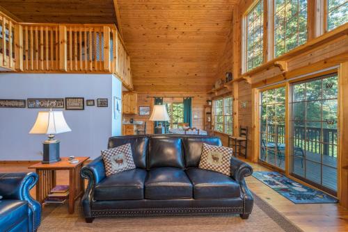 a leather couch in a living room with wooden ceilings at Christmas Tree Cabin Secluded Asheville Area Log Cabin with a View! in Old Fort