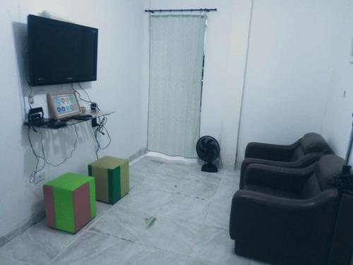 a living room with two chairs and a television at Casa Inteira e Tranquila em Taboão da Serra in Taboão da Serra