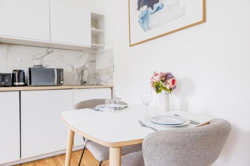Cosy Studio Etoile Friedland في باريس: مطبخ أبيض مع طاولة بيضاء وكراسي
