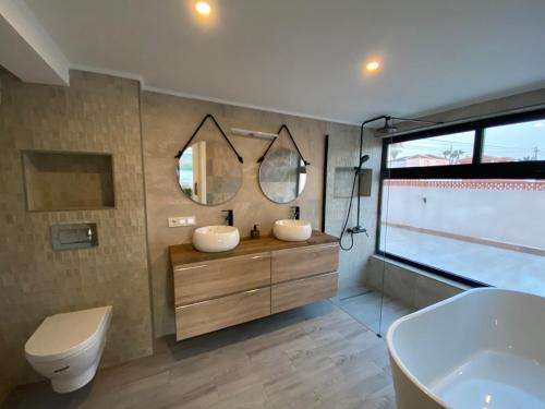 a bathroom with two sinks and a tub and a toilet at Pink Lagoon Villa in Torrevieja