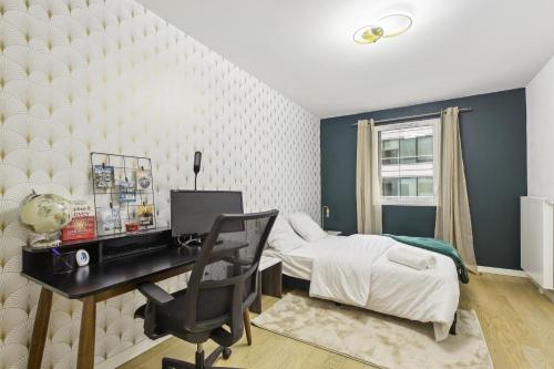 a bedroom with a bed and a desk with a computer at Chic apart with parking near Paris in Rueil-Malmaison