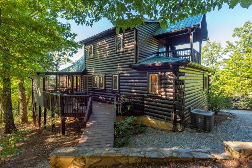 a log cabin in the woods with a wooden walkway leading to it at Summit Sunsets Pets & Year-Round Mountain Views! in Marion