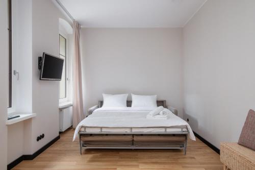 a white bedroom with a bed and a tv at Stary Browar Cosy Studio in Poznań