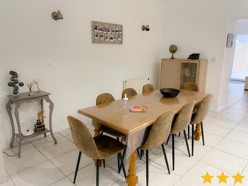 uma sala de jantar com uma mesa de madeira e cadeiras em Le Clos Des Oyats a Bleriot-Plage em Blériot-Plage