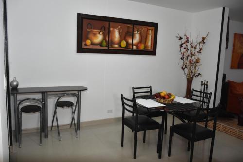 comedor con mesa y sillas y una foto en la pared en ApartaHotel Modelia con Parqueadero, en Bogotá