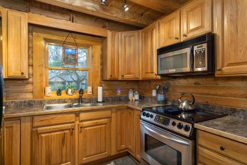 a kitchen with wooden cabinets and a stove and microwave at Stoney Creek Cabin Creekside Cabin Close to Town in Black Mountain