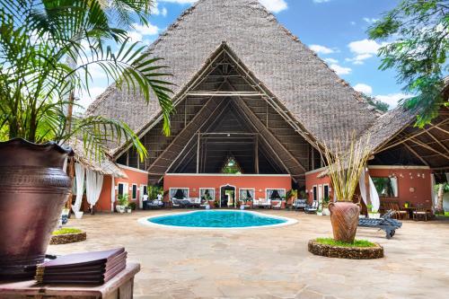 a resort with a swimming pool and a straw roof at Saffron Garden Malindi in Malindi