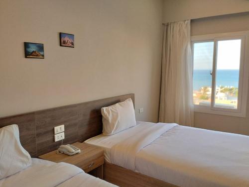 Al Dora Residence Suites Hurghada في الغردقة: غرفة فندقية بسريرين ونافذة
