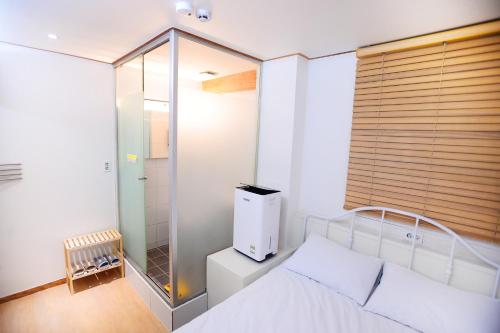 - une chambre avec une douche en verre et un lit dans l'établissement All Stay Inn Seoul, à Séoul