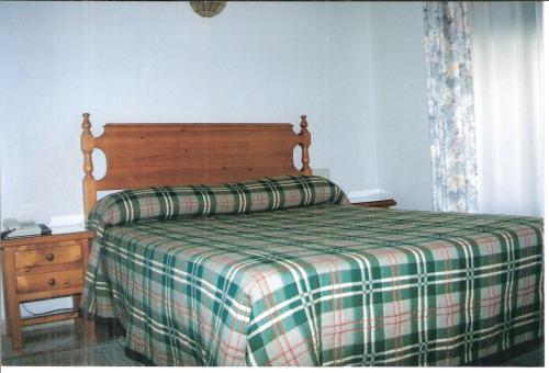 1 dormitorio con 1 cama con edredón de cuadros en Hostal Niza, en Badajoz