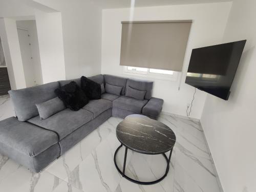 a living room with a gray couch and a table at Maestro I Apartment in Larnaca