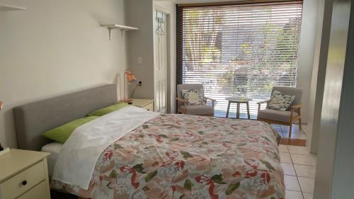 1 dormitorio con 1 cama, ventana y sillas en BNE24M1, en Slacks Creek