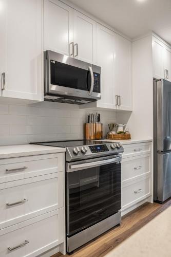 a kitchen with white cabinets and a microwave at Serene Peaks, Private Hot Tub, Peaceful in Radium Hot Springs