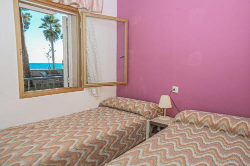 カンブリルスにあるPins i Mar Litoral BJOS- ONLY FAMILIESのベッドルーム1室(ベッド2台付)、ビーチを望む窓が備わります。