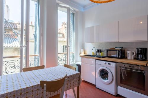 une cuisine avec une table et une machine à laver dans l'établissement Appartement T4 cours Julien proche Vieux-Port - parking gratuit, à Marseille