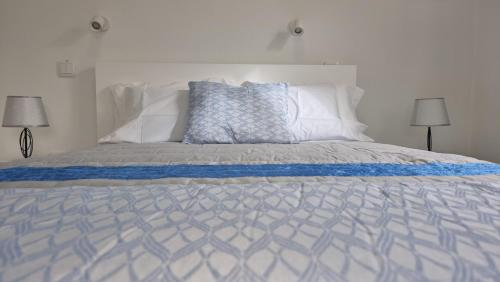 Cama blanca con sábanas y almohadas azules y blancas en Pico dos Anjos, en Porto Moniz