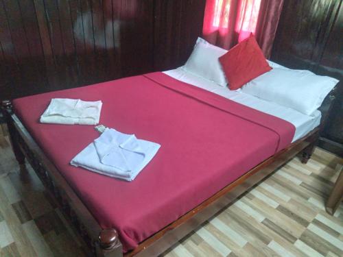 a large bed with pink sheets and towels on it at Homely Home stay in Kalpetta